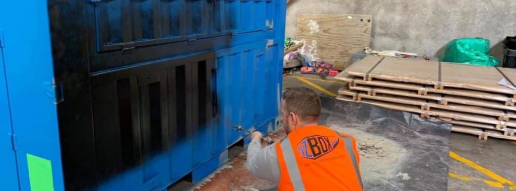 NZBOX staff member painting a shipping container with spray gun